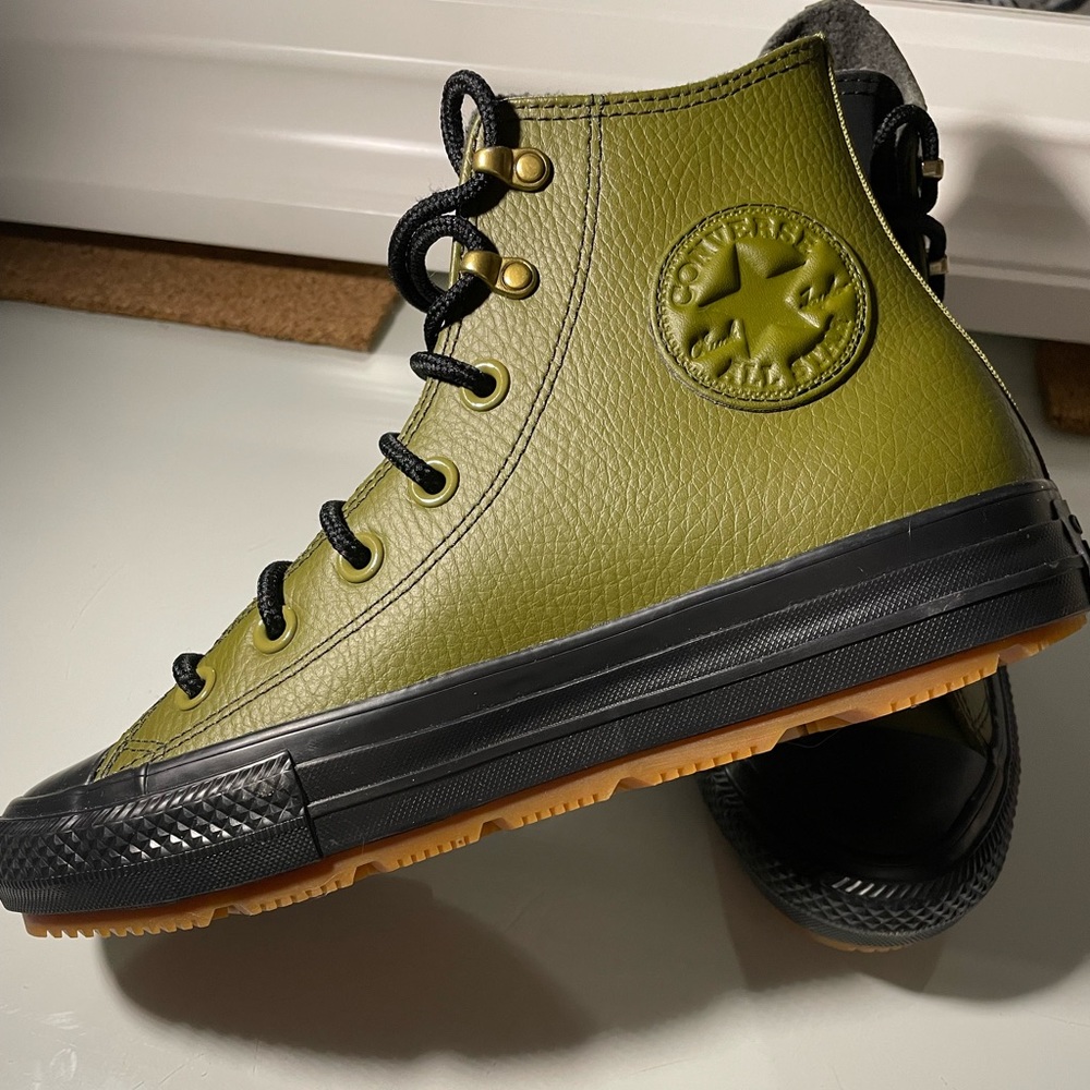 Converse All Star shoes. Olive green leather, with a black sole and black laces.